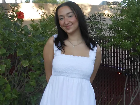 headshot of a person standing outside with foliage visible in the background