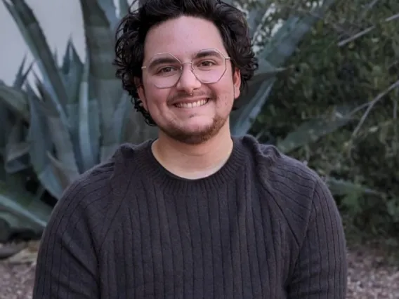 headshot of a person standing outside with grass and trees in the background