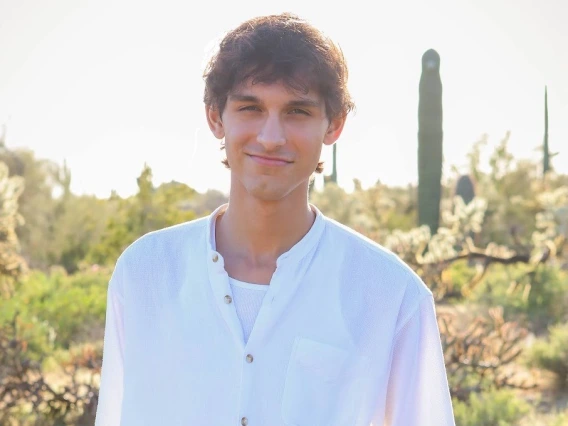 headshot of a person in front of an outdoor desert background