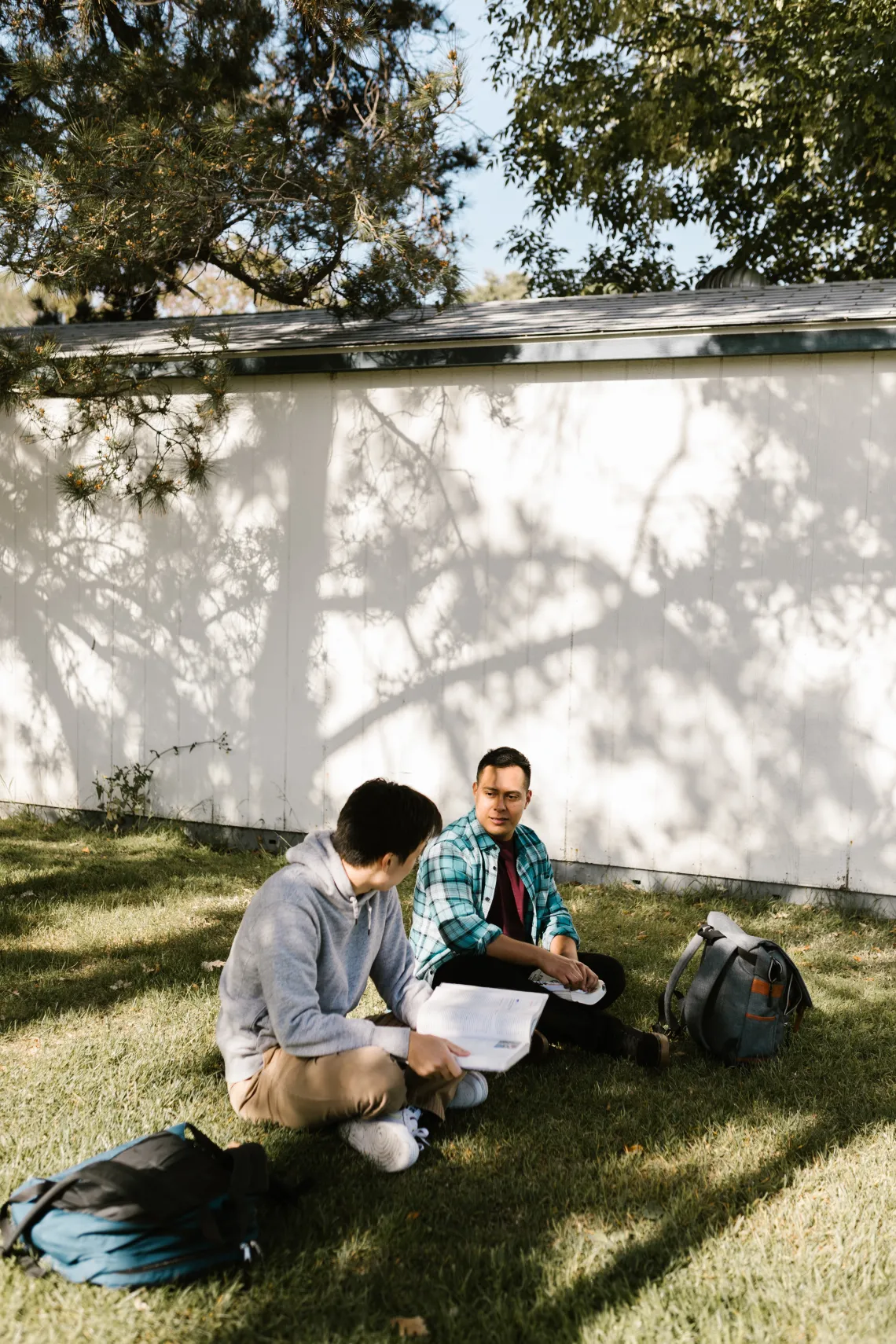 two people sitting in the grass talking